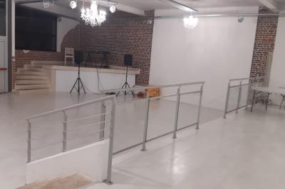 Salle lumineuse avec canapés, tables basses, bar moderne et décoration minimaliste, sous un plafond en verrière.