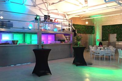 Salle lumineuse avec canapés, tables basses, bar moderne et décoration minimaliste, sous un plafond en verrière.