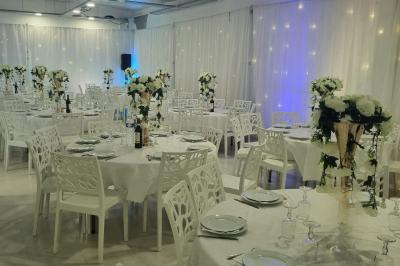 Salle lumineuse avec canapés, tables basses, bar moderne et décoration minimaliste, sous un plafond en verrière.