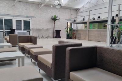 Salle lumineuse avec canapés, tables basses, bar moderne et décoration minimaliste, sous un plafond en verrière.