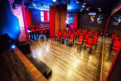 Salle lumineuse avec canapés, tables basses, bar moderne et décoration minimaliste, sous un plafond en verrière.