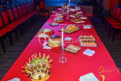 Salle lumineuse avec canapés, tables basses, bar moderne et décoration minimaliste, sous un plafond en verrière.