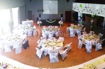Salle de réception animée avec de nombreuses personnes debout, éclairage chaleureux et décorations suspendues.