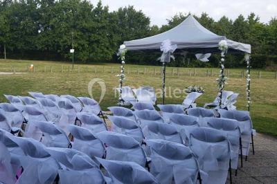 Salle de réception animée avec de nombreuses personnes debout, éclairage chaleureux et décorations suspendues.