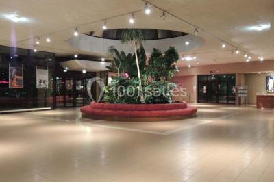 Salle de réception animée avec de nombreuses personnes debout, éclairage chaleureux et décorations suspendues.