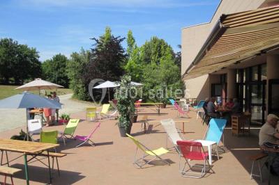 Salle de réception animée avec de nombreuses personnes debout, éclairage chaleureux et décorations suspendues.
