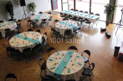 Salle de réception animée avec de nombreuses personnes debout, éclairage chaleureux et décorations suspendues.