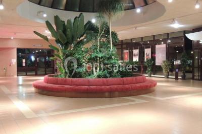 Salle de réception animée avec de nombreuses personnes debout, éclairage chaleureux et décorations suspendues.