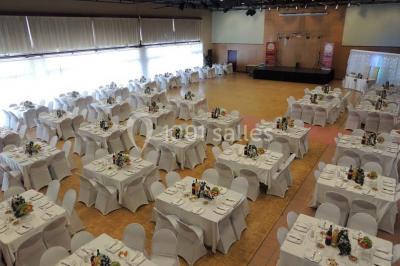 Salle de réception animée avec de nombreuses personnes debout, éclairage chaleureux et décorations suspendues.