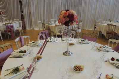 Salle de réception animée avec de nombreuses personnes debout, éclairage chaleureux et décorations suspendues.