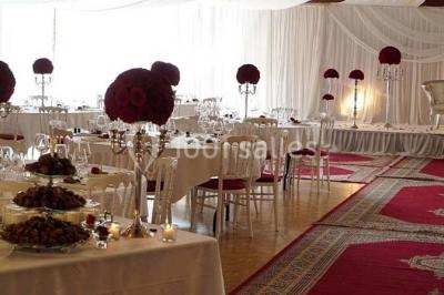 Salle de réception animée avec de nombreuses personnes debout, éclairage chaleureux et décorations suspendues.