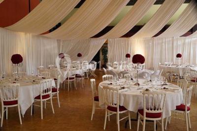 Salle de réception animée avec de nombreuses personnes debout, éclairage chaleureux et décorations suspendues.