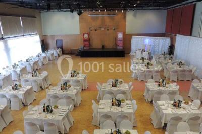 Salle de réception animée avec de nombreuses personnes debout, éclairage chaleureux et décorations suspendues.