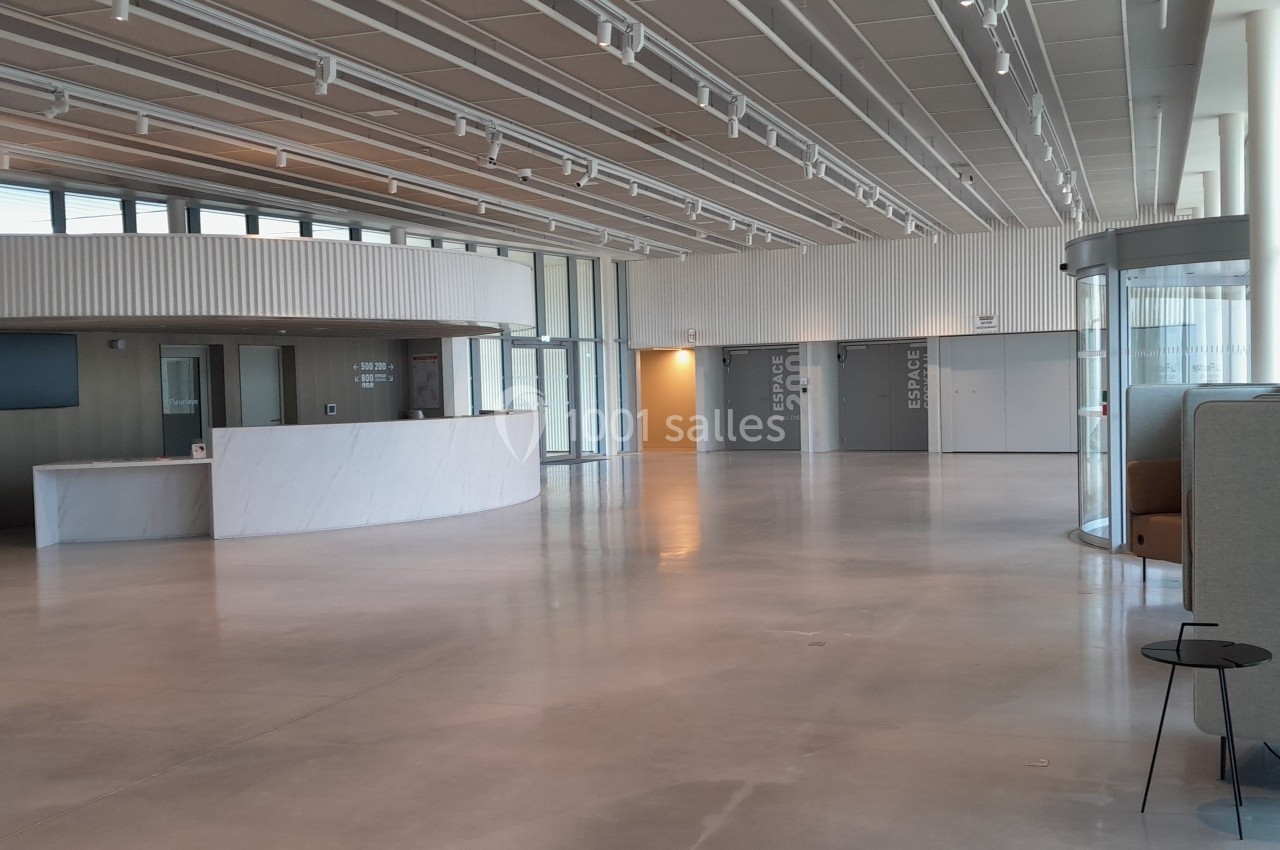 Hall spacieux et lumineux avec comptoir d'accueil, baies vitrées et mobilier moderne.