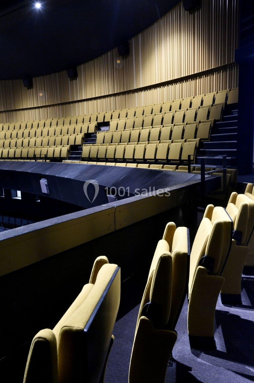 Salle de spectacle vide avec des rangées de sièges jaunes et un éclairage tamisé.