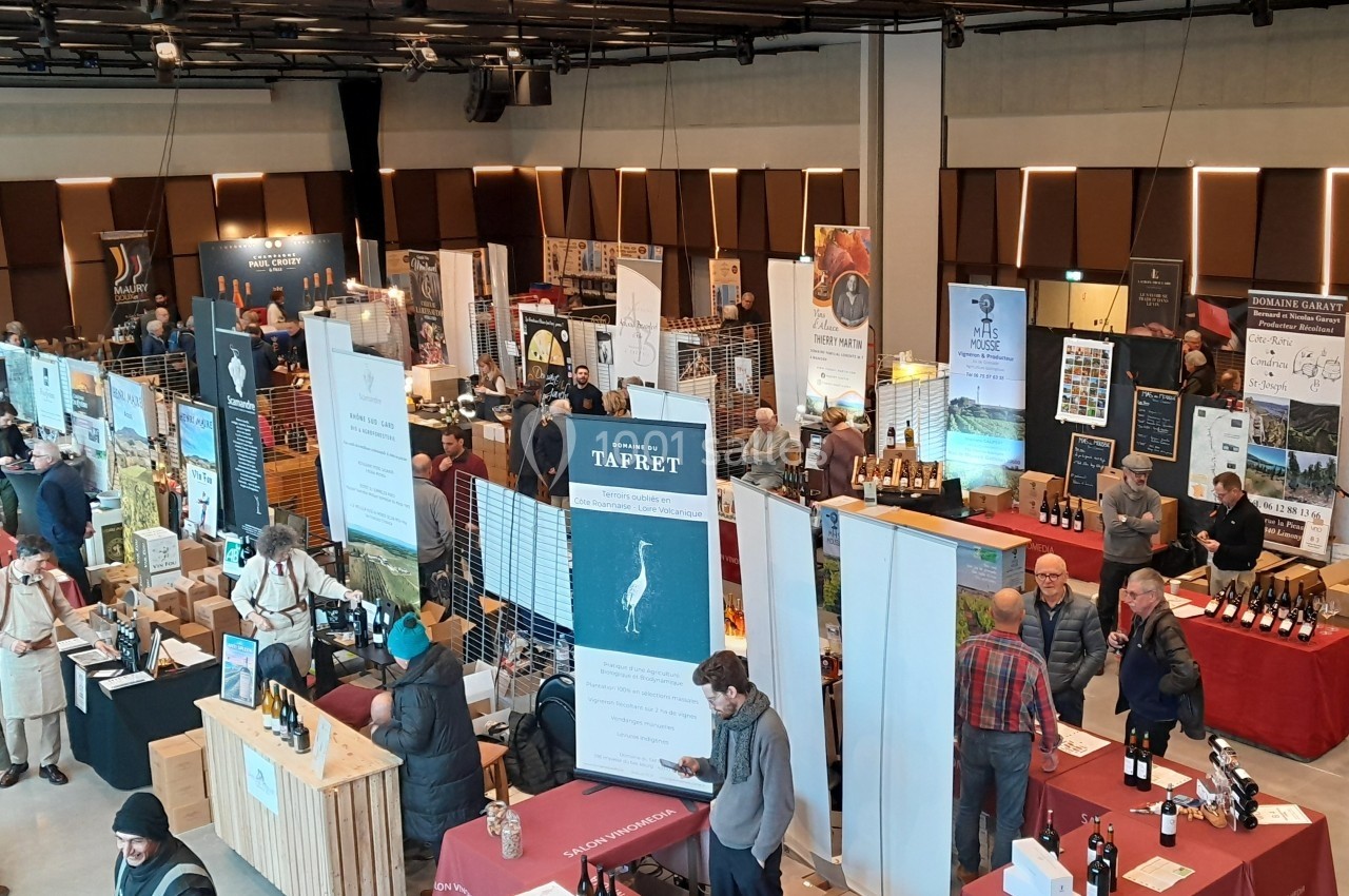 Vue d'un salon professionnel avec des stands de produits, des visiteurs et des exposants dans une grande salle lumineuse.
