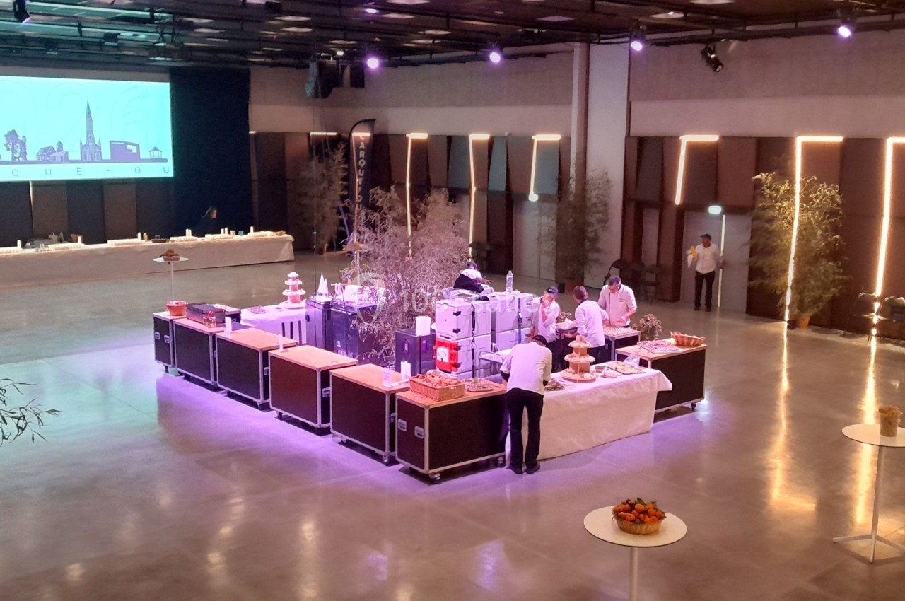 Salle de réception moderne avec un buffet en préparation, éclairage tamisé et décorations minimalistes.
