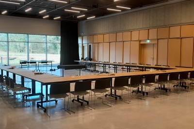 Miniature Location salle Carquefou (Loire-Atlantique) - Centre de Congrès la Fleuriaye #24 Salle de réunion avec une grande table en bois, des chaises orange et un écran noir monté sur un support.