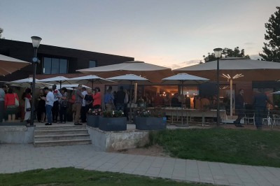 Paysage hivernal avec un terrain enneigé, des tables extérieures et un coucher de soleil vibrant au-dessus d'un lac.