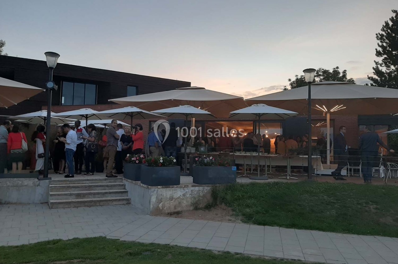 Groupe de personnes rassemblées sous des parasols sur une terrasse au crépuscule.