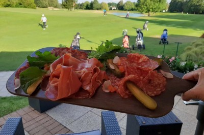 Paysage hivernal avec un terrain enneigé, des tables extérieures et un coucher de soleil vibrant au-dessus d'un lac.