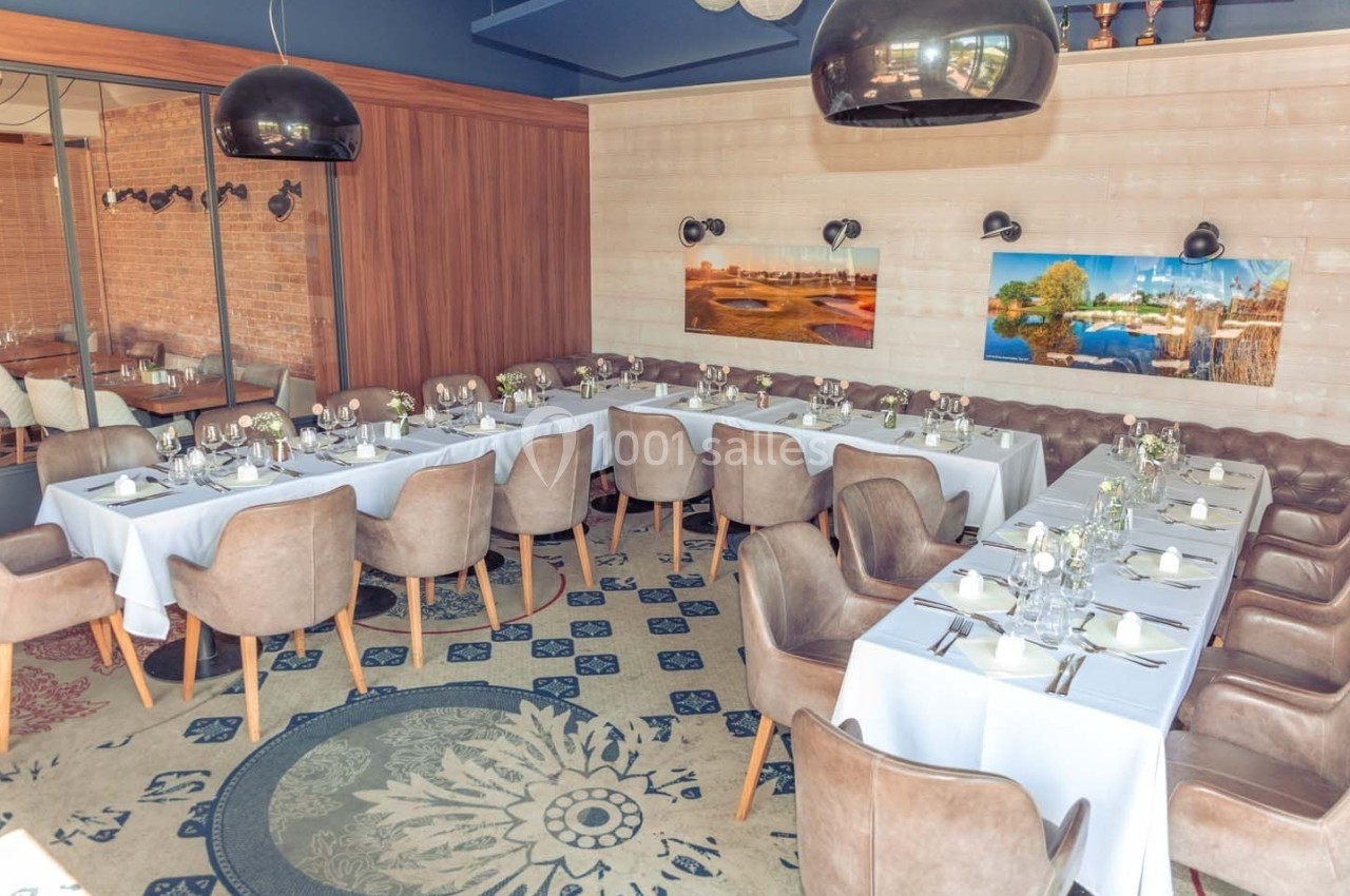 Salle de restaurant élégante avec tables dressées, nappes blanches, chaises rembourrées et décorations murales colorées.