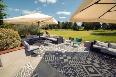 Paysage hivernal avec un terrain enneigé, des tables extérieures et un coucher de soleil vibrant au-dessus d'un lac.