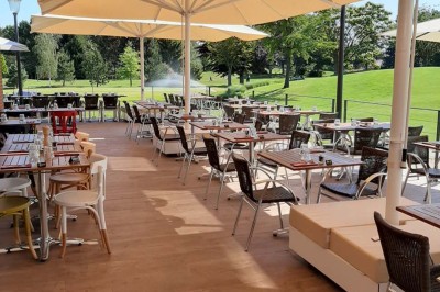 Paysage hivernal avec un terrain enneigé, des tables extérieures et un coucher de soleil vibrant au-dessus d'un lac.