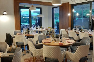 Paysage hivernal avec un terrain enneigé, des tables extérieures et un coucher de soleil vibrant au-dessus d'un lac.