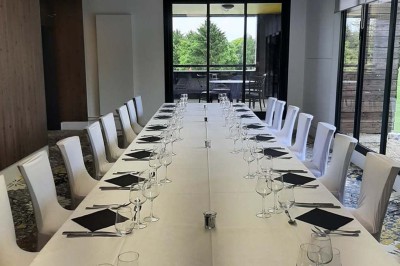 Paysage hivernal avec un terrain enneigé, des tables extérieures et un coucher de soleil vibrant au-dessus d'un lac.