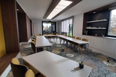 Paysage hivernal avec un terrain enneigé, des tables extérieures et un coucher de soleil vibrant au-dessus d'un lac.