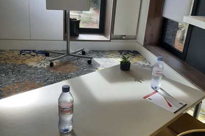 Paysage hivernal avec un terrain enneigé, des tables extérieures et un coucher de soleil vibrant au-dessus d'un lac.