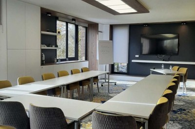 Paysage hivernal avec un terrain enneigé, des tables extérieures et un coucher de soleil vibrant au-dessus d'un lac.