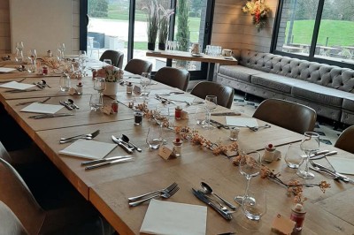 Paysage hivernal avec un terrain enneigé, des tables extérieures et un coucher de soleil vibrant au-dessus d'un lac.