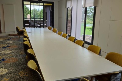 Paysage hivernal avec un terrain enneigé, des tables extérieures et un coucher de soleil vibrant au-dessus d'un lac.