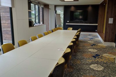 Paysage hivernal avec un terrain enneigé, des tables extérieures et un coucher de soleil vibrant au-dessus d'un lac.