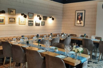 Paysage hivernal avec un terrain enneigé, des tables extérieures et un coucher de soleil vibrant au-dessus d'un lac.