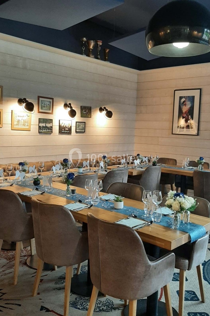 Salle de restaurant élégante avec tables dressées, chaises en velours, décorations murales et éclairage chaleureux.