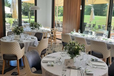 Paysage hivernal avec un terrain enneigé, des tables extérieures et un coucher de soleil vibrant au-dessus d'un lac.