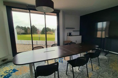 Paysage hivernal avec un terrain enneigé, des tables extérieures et un coucher de soleil vibrant au-dessus d'un lac.