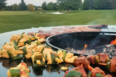 Paysage hivernal avec un terrain enneigé, des tables extérieures et un coucher de soleil vibrant au-dessus d'un lac.
