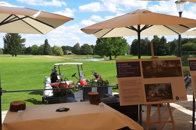 Paysage hivernal avec un terrain enneigé, des tables extérieures et un coucher de soleil vibrant au-dessus d'un lac.