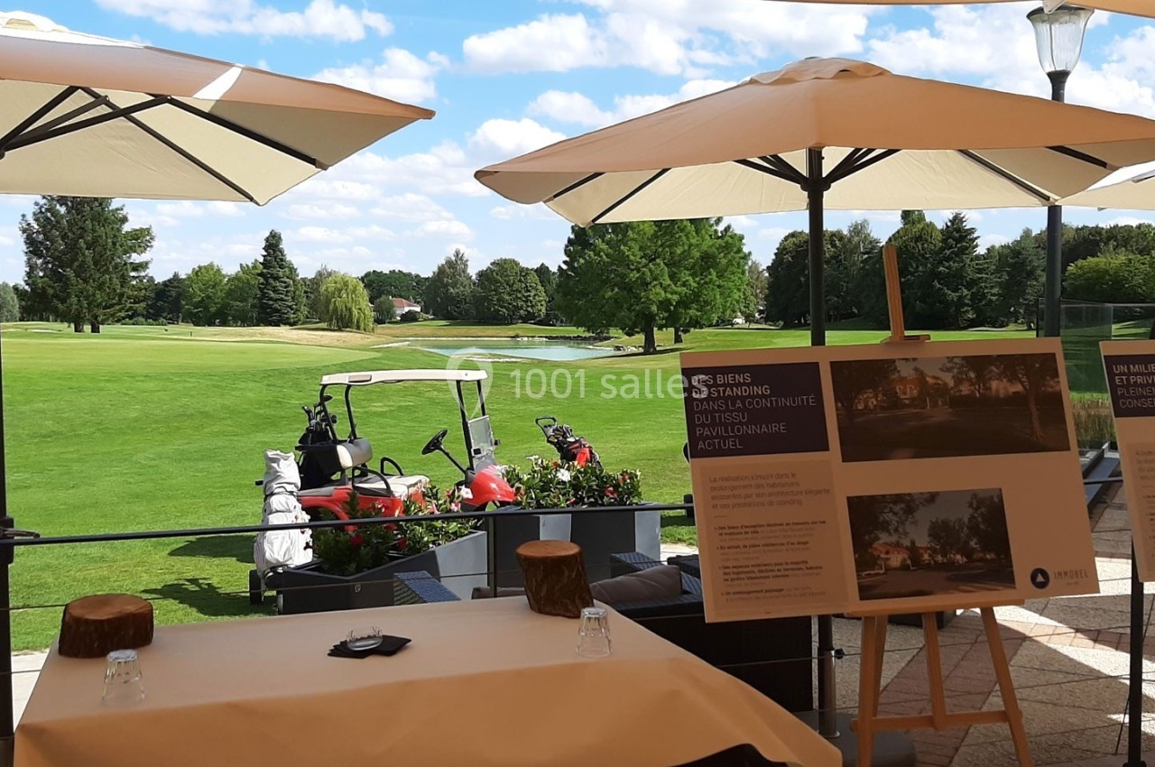 Panneaux d'information disposés sur une terrasse avec vue sur un terrain de golf sous un ciel ensoleillé.