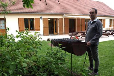 Terrasse ensoleillée avec tables et chaises en bois, entourée de verdure et d'une façade recouverte de lierre.