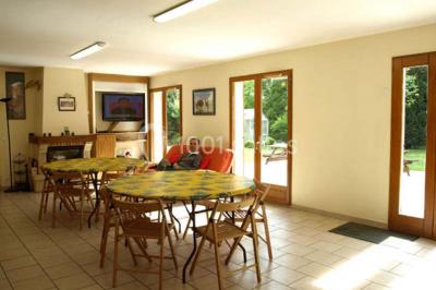 Terrasse ensoleillée avec tables et chaises en bois, entourée de verdure et d'une façade recouverte de lierre.
