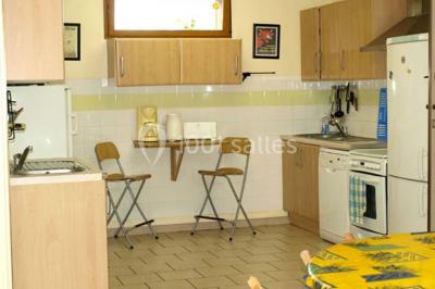 Terrasse ensoleillée avec tables et chaises en bois, entourée de verdure et d'une façade recouverte de lierre.