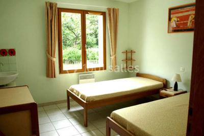 Terrasse ensoleillée avec tables et chaises en bois, entourée de verdure et d'une façade recouverte de lierre.