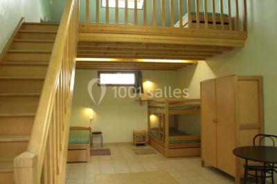 Terrasse ensoleillée avec tables et chaises en bois, entourée de verdure et d'une façade recouverte de lierre.