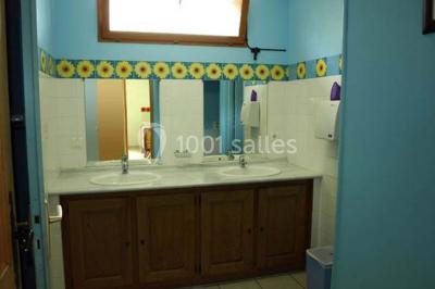 Terrasse ensoleillée avec tables et chaises en bois, entourée de verdure et d'une façade recouverte de lierre.