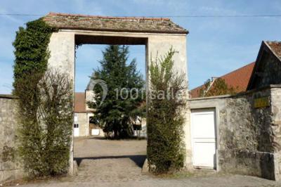 Terrasse ensoleillée avec tables et chaises en bois, entourée de verdure et d'une façade recouverte de lierre.
